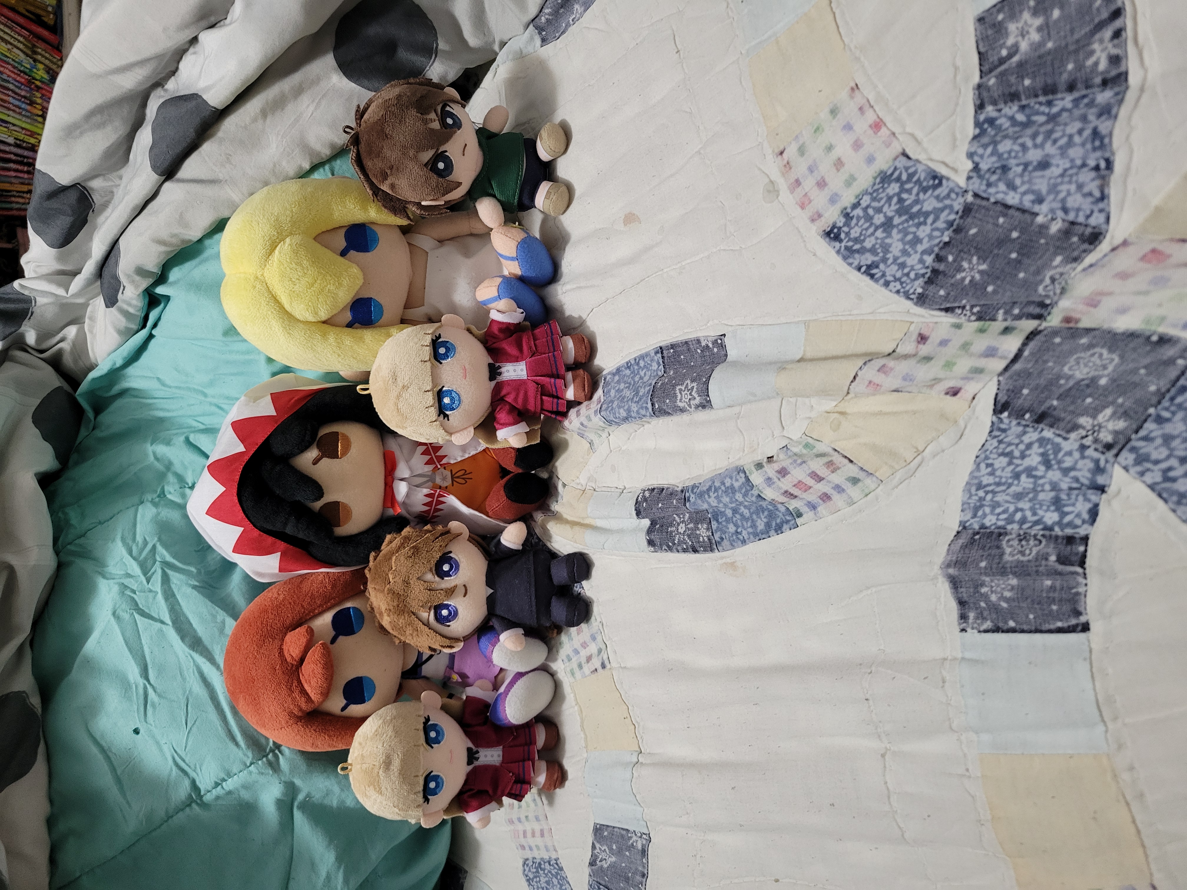 Relena, Kairi, Duo, Garnet, Relena, Naminé, and Heero plushes lay against blanket on bed.